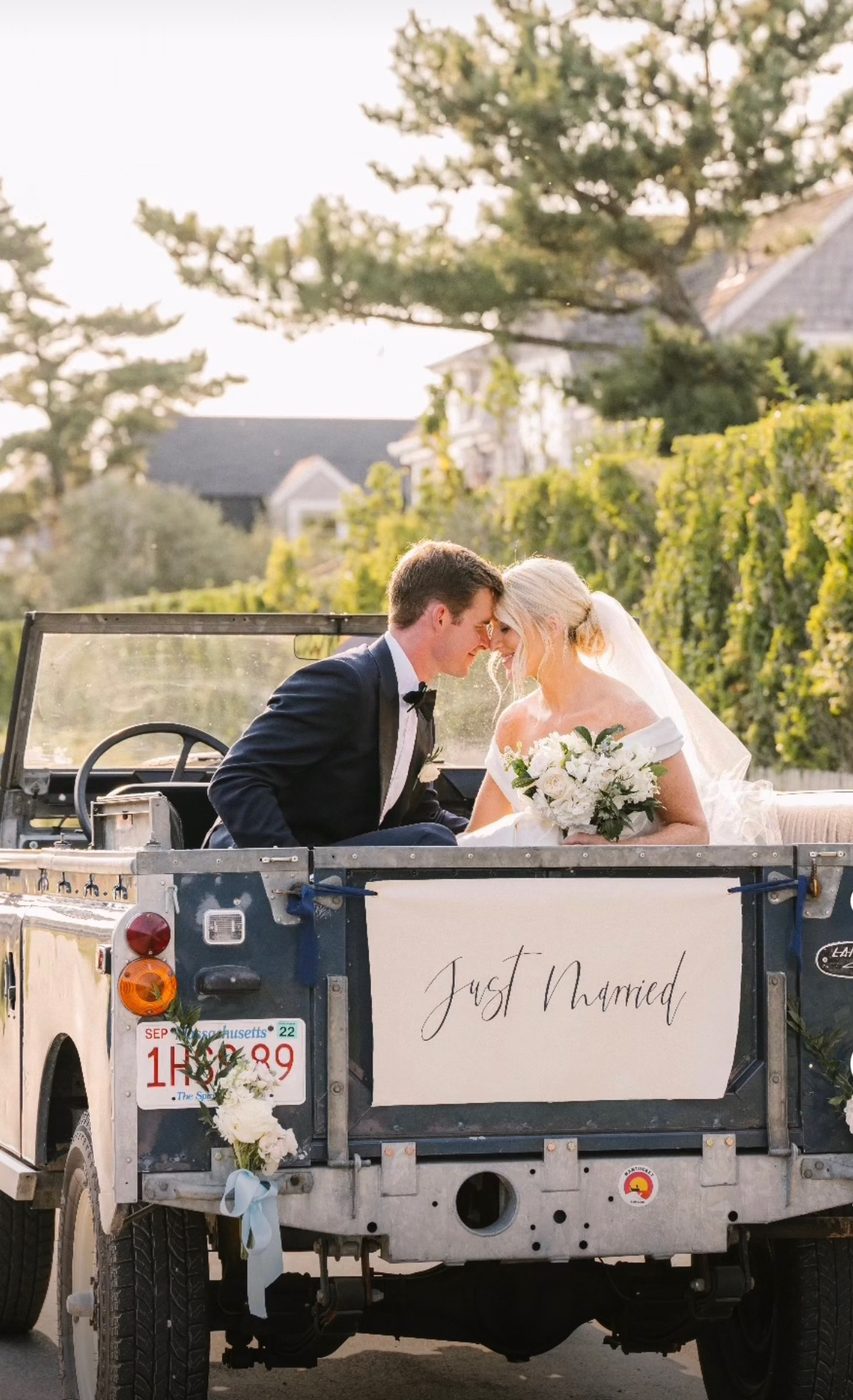 The classic Land Rover from behind, a Just Married banner across the tailgate.